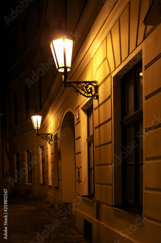 wall lamps in narrow street in old town of Lübeck at night