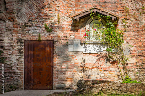 Fototapeta Naklejka Na Ścianę i Meble -  Entrance and window in a mediterranean red brick wall in Siena