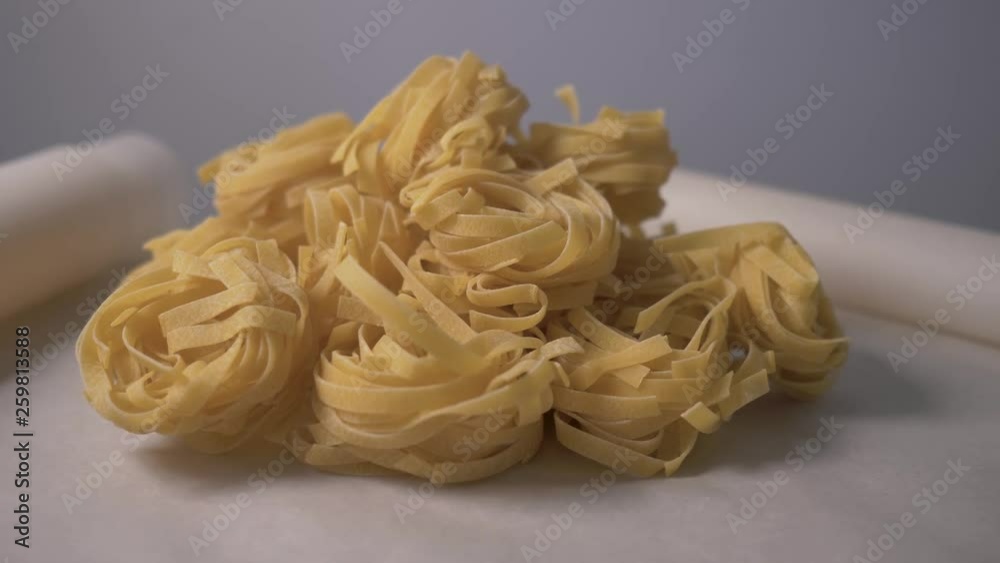 Fettuccine pastas nests lie on the table. Cooking fettuccine pastas nests. Food video. Concept: footage for the recipe. 4K Fettuccine pastas nests lie on the table. Cooking fettuccine pastas nests. Food video. Concept: footage for the recipe. 4K