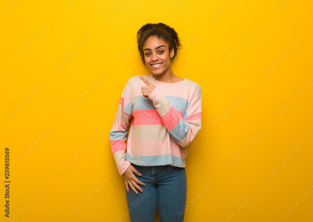 Young black african american girl with blue eyes smiling and pointing to the side Young black african american girl with blue eyes smiling and pointing to the side