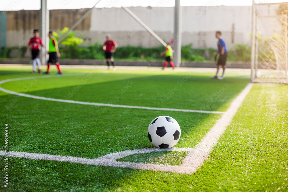 soccer ball on green artificial turf at corner of football field with blurry players background soccer ball on green artificial turf at corner of football field with blurry players background