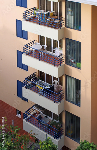 a row of balconies with tables and chairs in an orange and blue concrete apartme Fototapeta