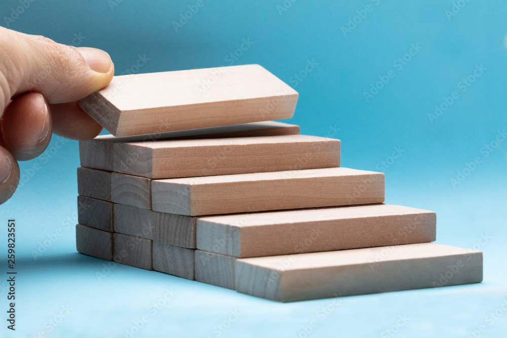 Hand Arranging Wooden Block On Blue Background