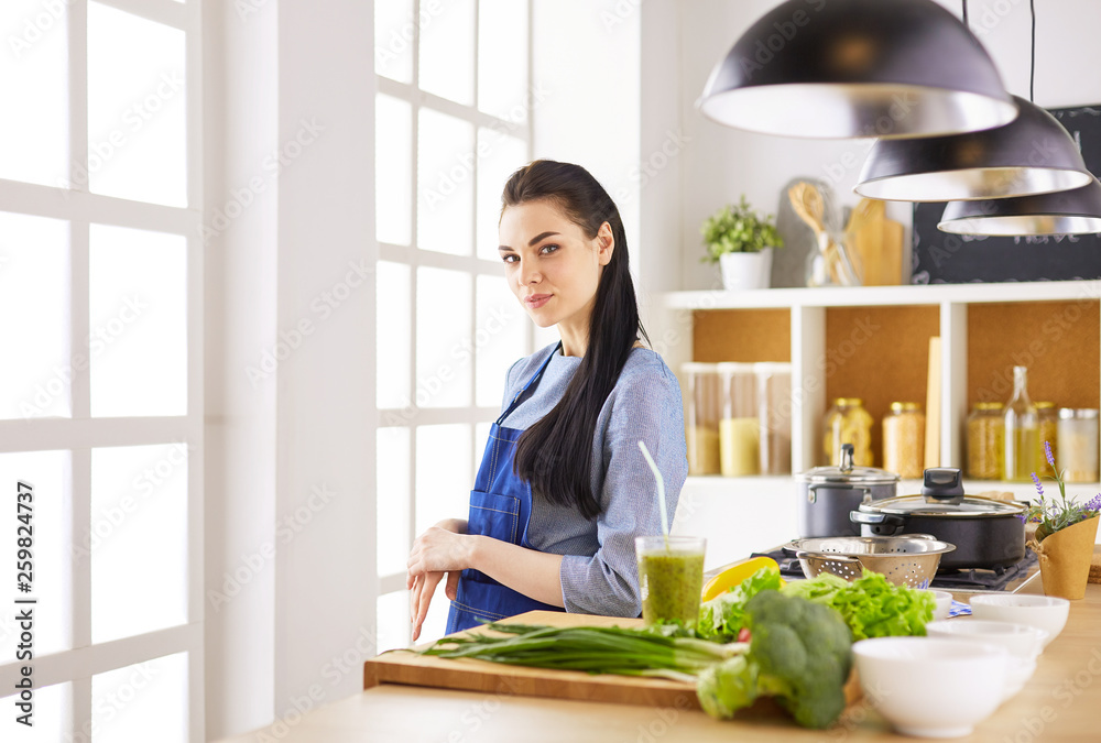 Portrait of young woman standing with arms crossed against kitchen background Portrait of young woman standing with arms crossed against kitchen background