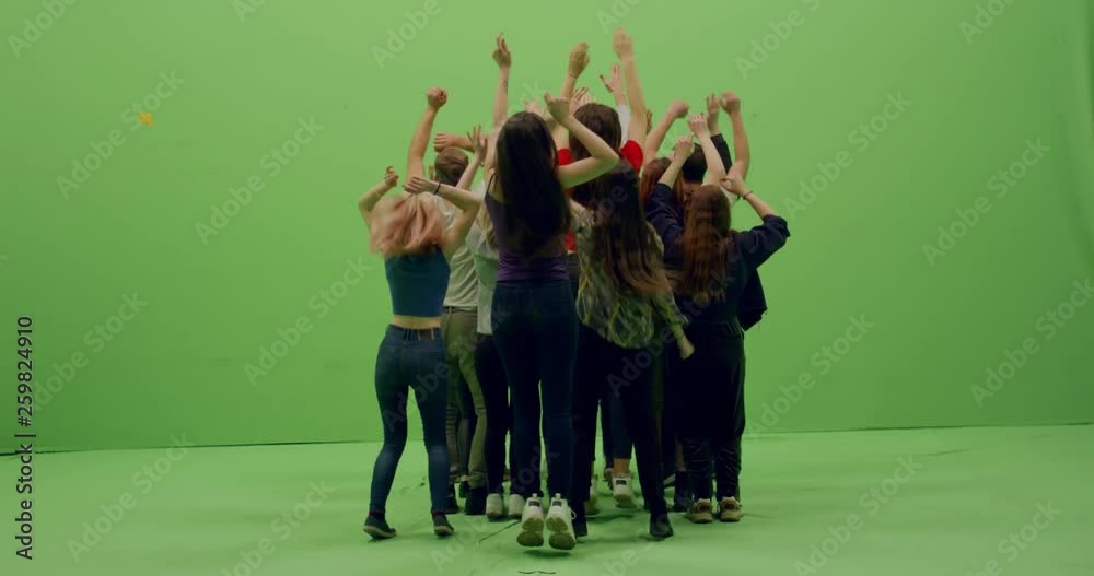 GREEN SCREEN CHROMA KEY Back view group of young people dancing and jumping with hands in the air. 4K UHD ProRes 4444
