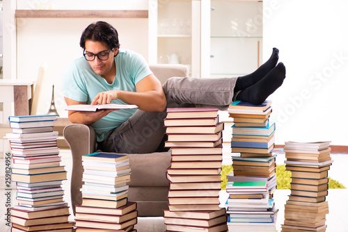 Male student with many books at home 