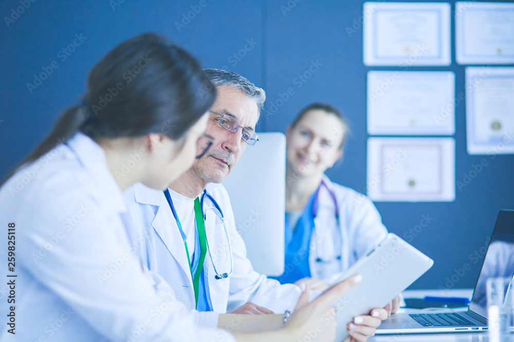 Serious medical team using a laptop in a bright office Serious medical team using a laptop in a bright office