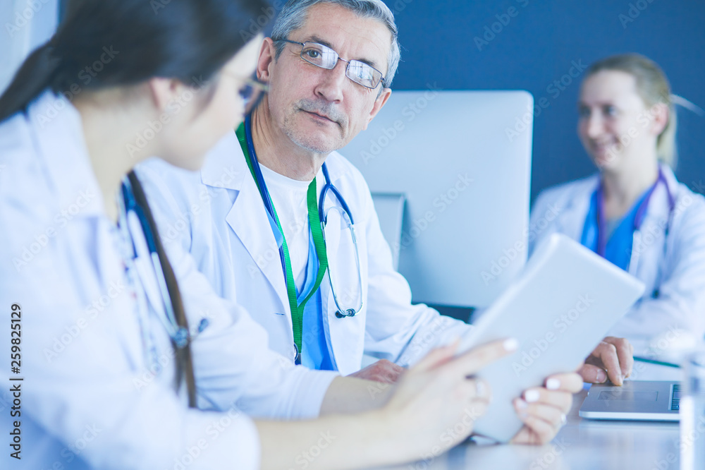 Serious medical team using a laptop in a bright office Serious medical team using a laptop in a bright office