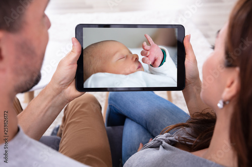Couple Looking At Baby On Digital Tablet