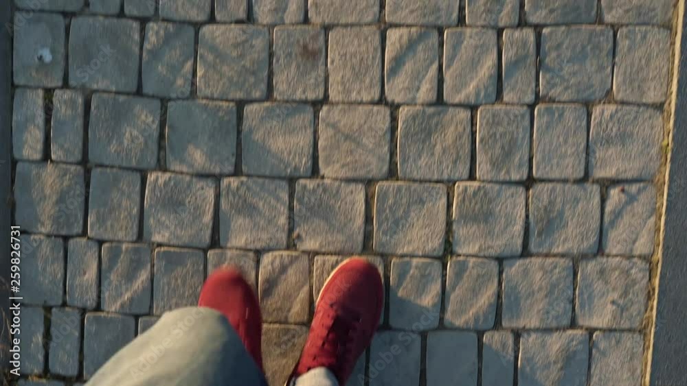 Top view of male legs in red sneakers walking along the sidewalk Top view of male legs in red sneakers walking along the sidewalk
