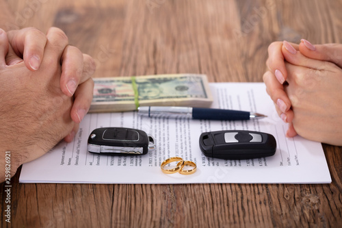 Hands On Divorce Document With Wedding Rings And Car Keys