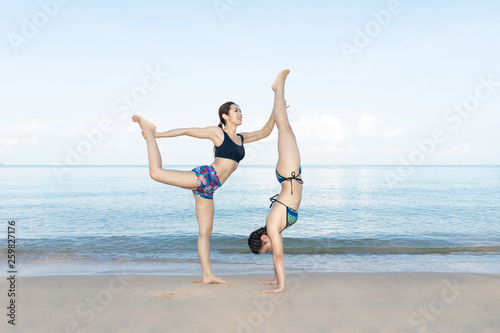 Healthy women are exercising with yoga on the beach in the blue sky.