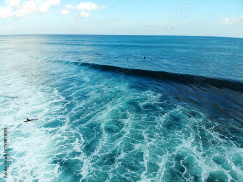 Aerial view of surfer on the waves, surfers on their board waiting the waves, big waves tropical blue ocean, drone view of surfer catching the blue waves, Bali, Indonesia photo