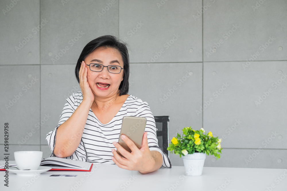 An old Asian woman looking at mobile phone and looking shock and horrify. An old Asian woman looking at mobile phone and looking shock and horrify.
