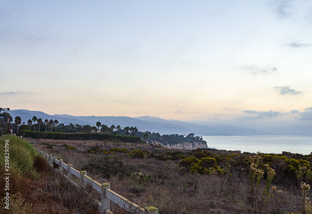 fence along cliff with ocean view with fog