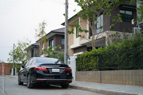 black modern car parked on road of village house © sutichak