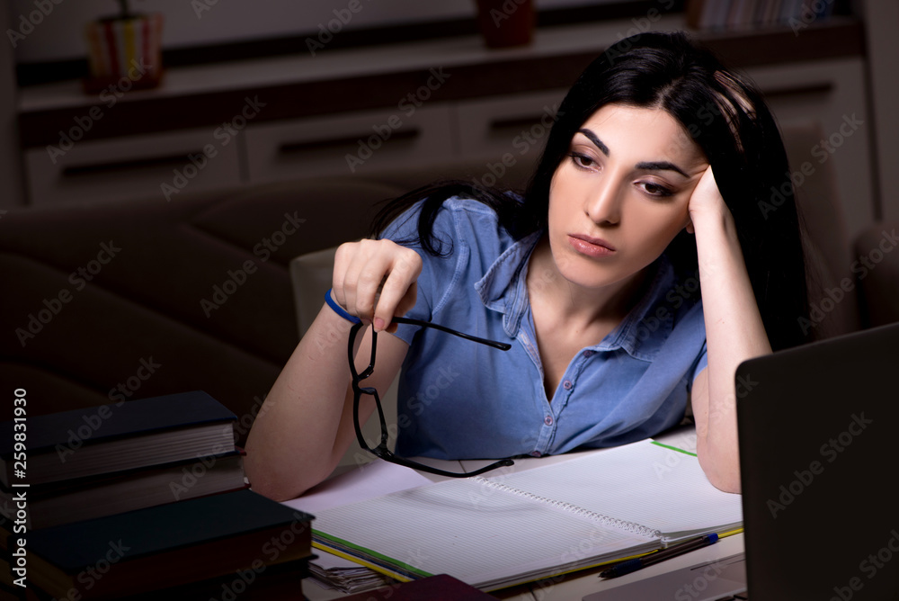 Young female student preparing for exams at night time 