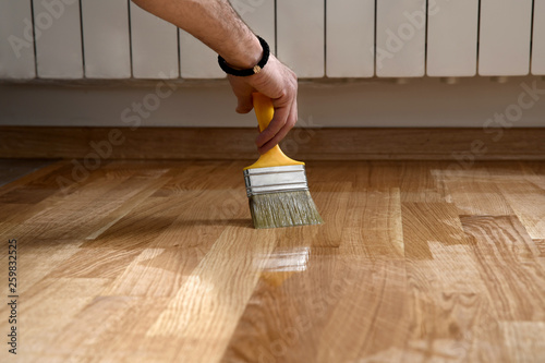 Home renovation parquet. Varnish paintbrush strokes on a wooden photo