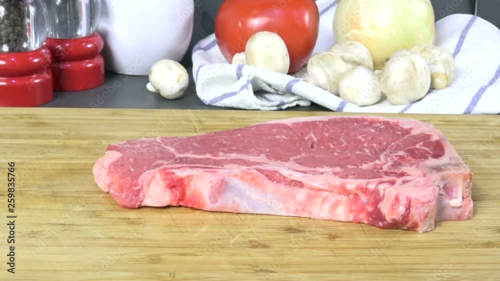 Placing a raw New York Strip steak on a cutting board