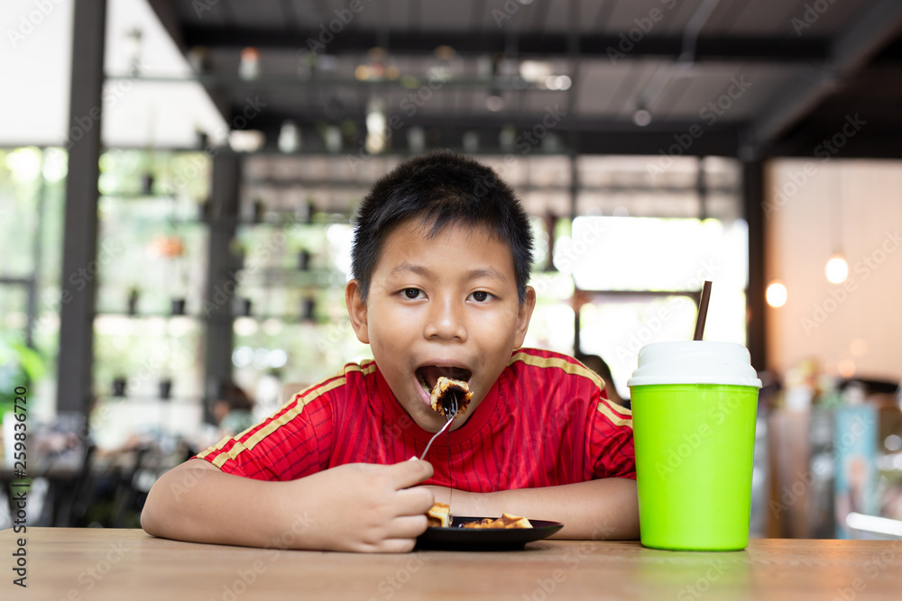 Happy face asian boy enjoy eating chocolate waffle in restaurant. Happy face asian boy enjoy eating chocolate waffle in restaurant.