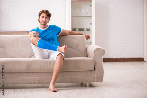 Leg injured young man on the sofa