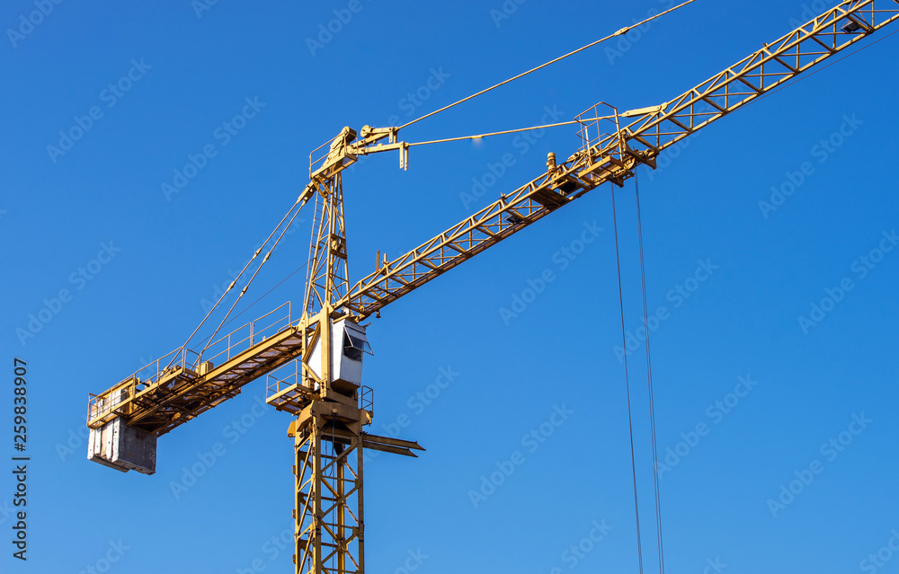 real high yellow crane tower isolate on blue sky background real high yellow crane tower isolate on blue sky background