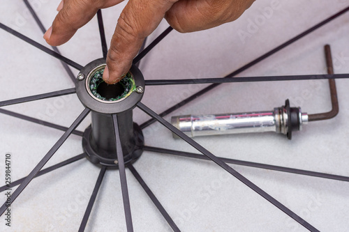  Technician man hand repairing and lubricate the bicycle wheel bearing and adjust by hex key. Maintenance concept.