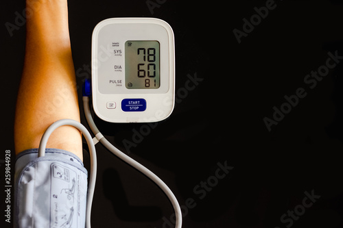 Woman take care for health,using sphygmomanometer to measure blood pressure,pulse and heart rate by self,isolated on dark background. Healthcare and hypotension concept. photo