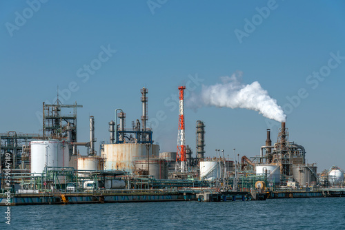 Scene of Oil refinery industial zone beside the river on working hour which have Steam smoke, factory and industry with pollution concept
