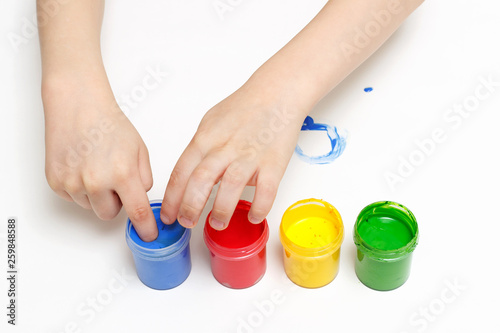 A child draws with colorful paint with his fingers on white paper.