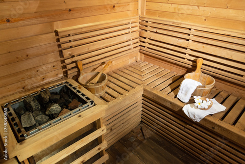 Empty wooden traditional sauna room.Hot stone, wooden bucket with accessories in the spa room.Selective focus