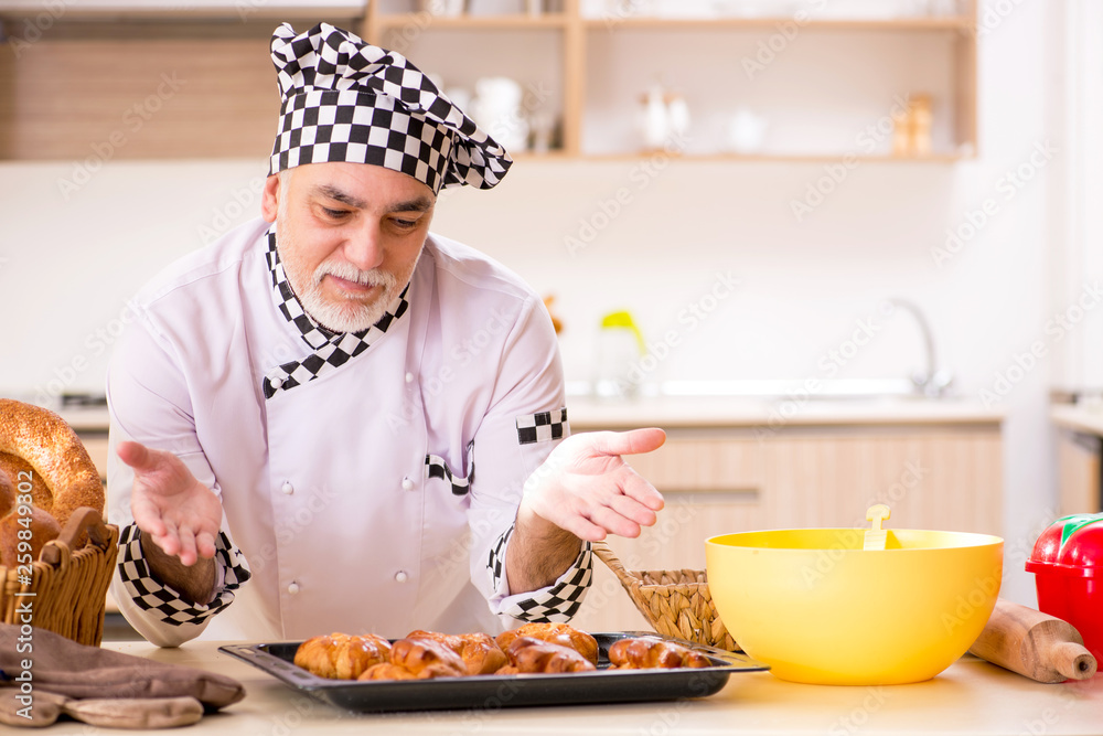 Old male baker working in the kitchen Old male baker working in the kitchen