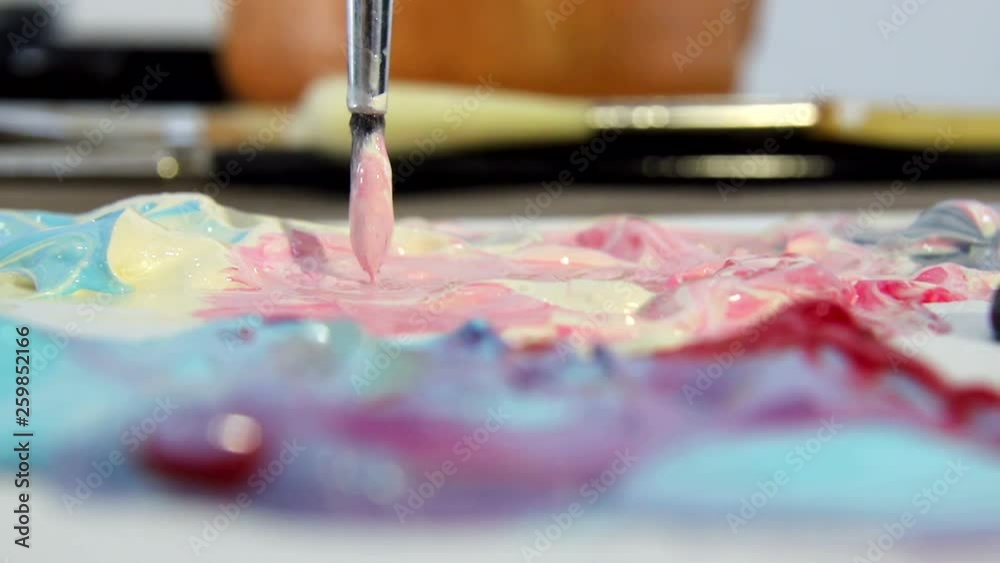 Artist mixes different colors of acrylic paint with a brush for drawing. Preparation of colors for drawing pictures Artist mixes different colors of acrylic paint with a brush for drawing. Preparation of colors for drawing pictures