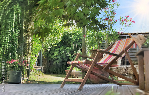 lounge chair on a wooden terrace in a greenery garden at summer