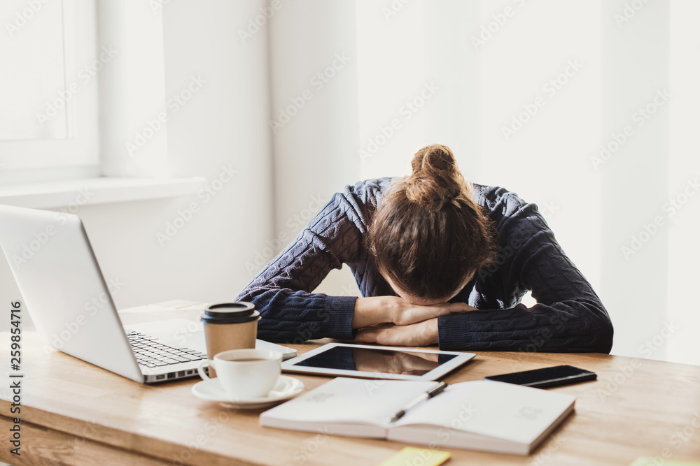 © kite_rin - Tired and overworked business woman. Young exhausted girl sleeping on table during her work using laptop, digital tablet and smartphone. Entrepreneur, freelance worker or student in stress concept