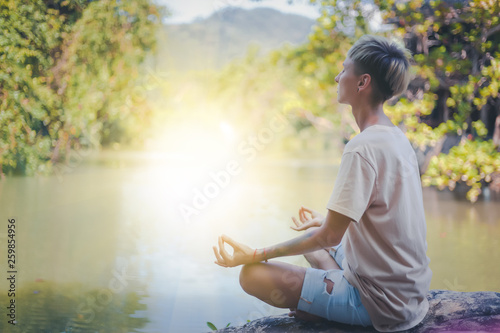 woman practices yoga and meditates in the lotus position, outdoor, lake in mountain