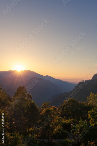 Bright stunning amazing sunrise in the mountains of Sri Lanka, the sun rises from behind the mountains. Beautiful landscape