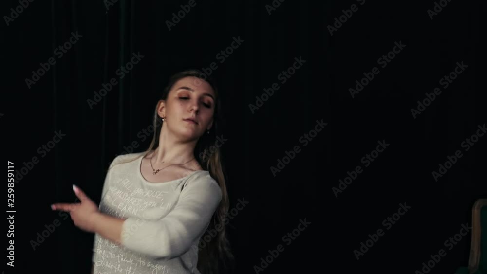 Young beautiful girl dancing contemporary in training or performing in a dark room with a green chair. Slow motion. Young beautiful girl dancing contemporary in training or performing in a dark room with a green chair. Slow motion.
