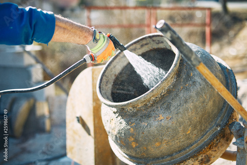 Canvastavla Construction worker on a cement / concrete mixer cleaning remaining cement