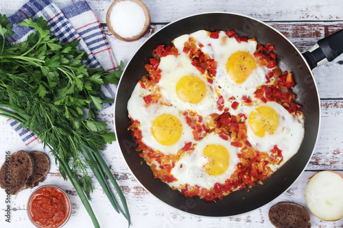 Shakshouka with five cooked eggs on top of tomato sauce in cast iron skillet
