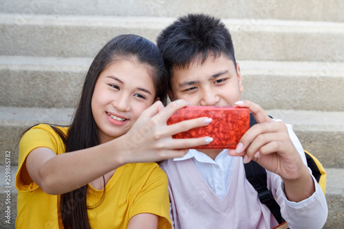 Teenager boy and girl sitting on stair smartphone