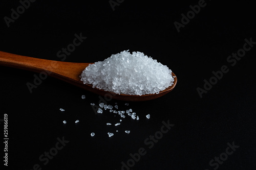a spoonful of coarse sea salt on a black background