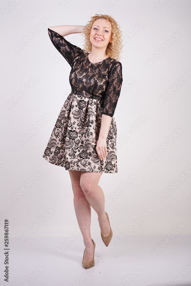 pretty blonde adult woman wearing lace city dress and posing on white background isolated. fashion girl in the fashionable short evening dress in the studio. pretty blonde adult woman wearing lace city dress and posing on white background isolated. fashion girl in the fashionable short evening dress in the studio.