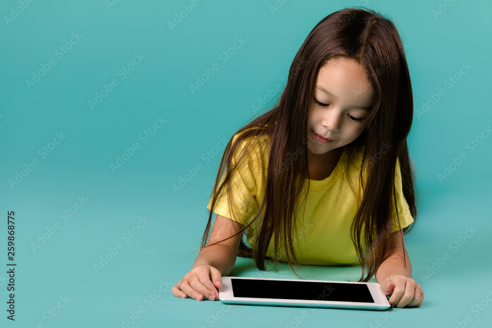 cute little child girl using tablet computer on blue background cute little child girl using tablet computer on blue background
