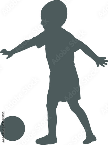 Silhouette of a child playing football. The boy hits the ball.
