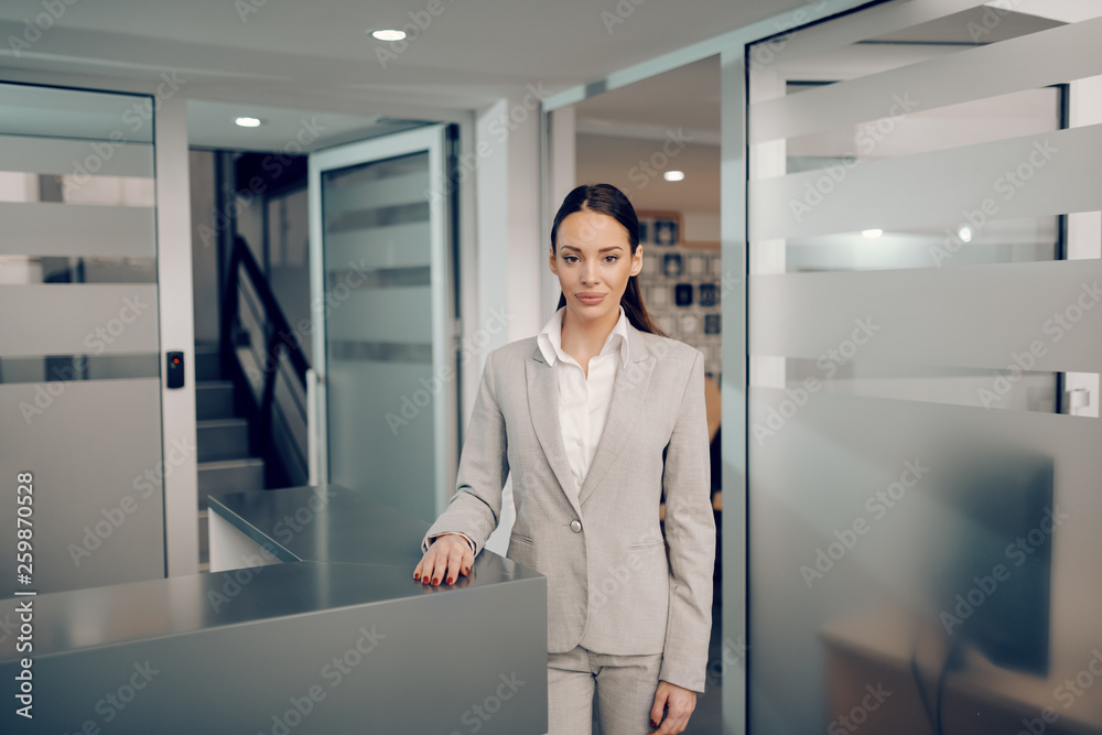 Fototapeta premium Portrait of young Caucasian brunette in formal wear standing at lobby in firm. The ones who are crazy enough to think they can change the world, are the ones that do.