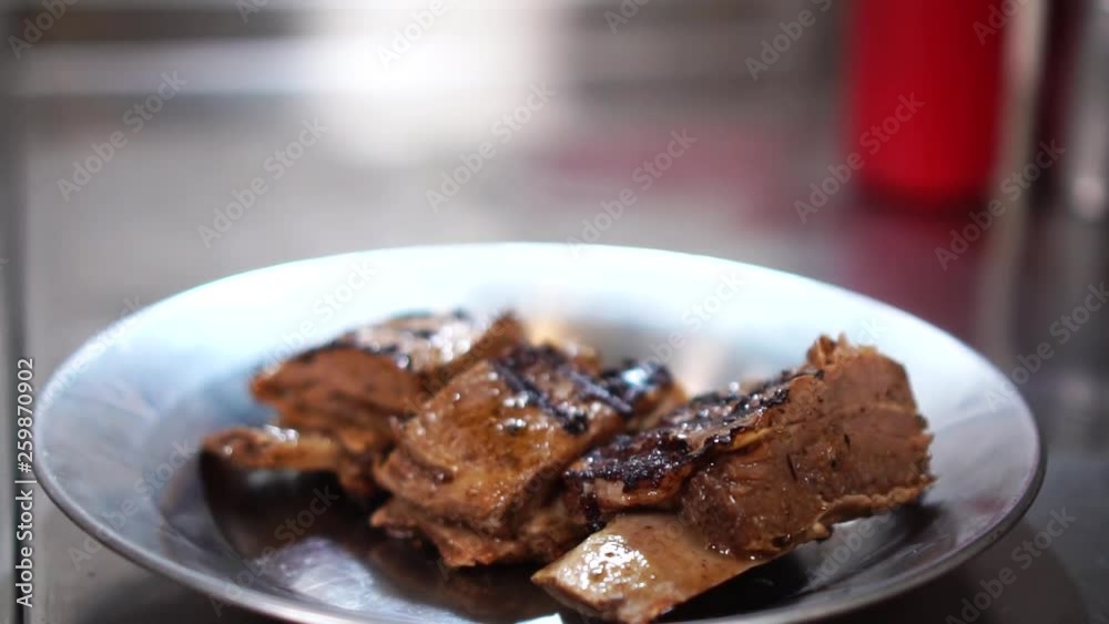 Detailed close up view on delicious fried pork ribs in hot juicy sauce on silver plate Detailed close up view on delicious fried pork ribs in hot juicy sauce on silver plate
