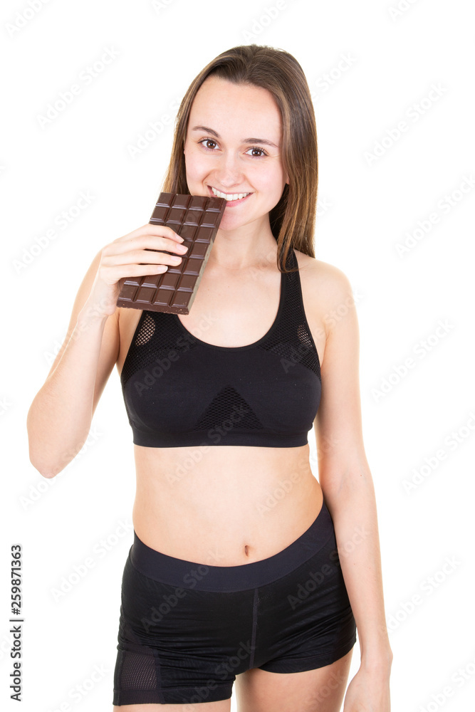 Young sporty woman in studio eating chocolate bar Young sporty woman in studio eating chocolate bar