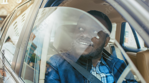 Traveling Young Man Rides on a Passenger Seat of a Car, Opens Window and Looks on a Big City in Wonder.