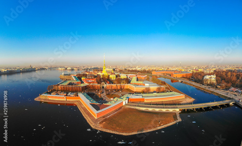 Beautifull aerial view of the Petropavlovsky fortress in sunny spring day. Golden tall spire of famous Peter and Paul Cathedral on the blue sky background. Historical centre of St. Petersburg, Russia. photo